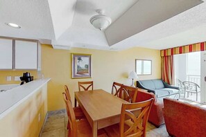 Ein Essbereich mit Holztisch und -stühlen, einer Küchenzeile und einem Sofa mit Blick nach draußen.