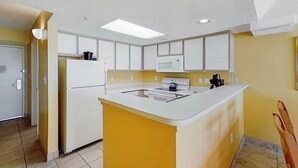 Una cucina compatta con isola centrale, mobili bianchi e forno a microonde.