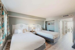 Ein Hotelzimmer mit zwei Betten, einem Badezimmer mit Dusche und einem begehbaren Kleiderschrank mit aufgehängter Kleidung.