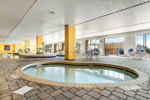 Ein Poolbereich im Innenbereich mit Fliesenboden, Liegestühlen und einem Pool mit gefliestem Rand.