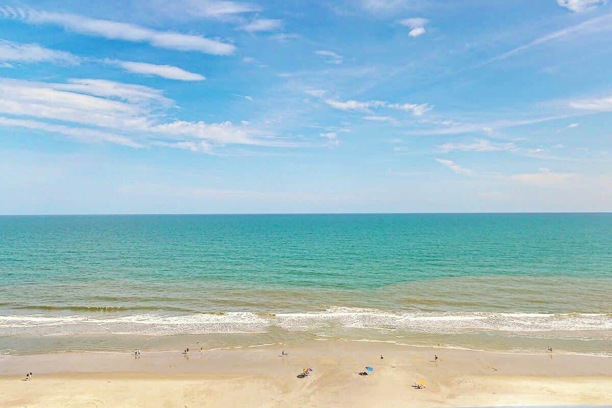 Une plage avec un ciel dégagé et une eau calme.