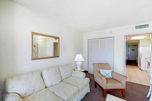 Ein Wohnzimmer mit Sofa, Sessel, Lampe und einem Spiegel an der Wand.