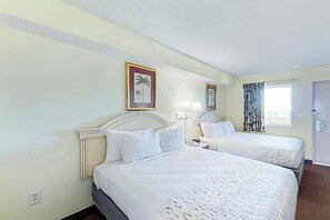 Ein Hotelzimmer mit zwei Betten, einem Nachttisch, einer Lampe und einem Fenster mit Vorhängen.
