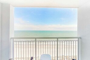 Ein Zimmer mit Blick auf einen Strand durch die Balkonbrüstung.