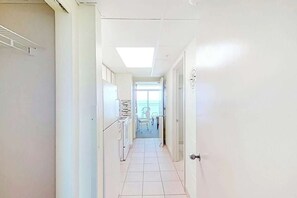 Un couloir doté d’un sol carrelé, d’un luminaire au plafond et d’une porte sur laquelle est apposé un panneau circulaire.