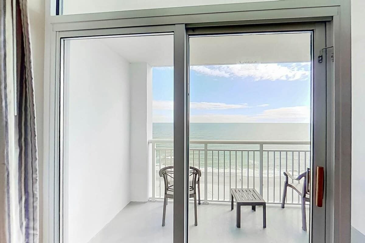 Ein Balkon mit Blick auf das Meer, ein Tisch und zwei Stühle.