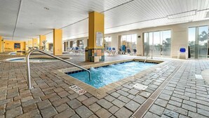 Ein Hallenbad mit Ziegelboden, Liegestühlen und ungehinderter Aussicht nach draußen.