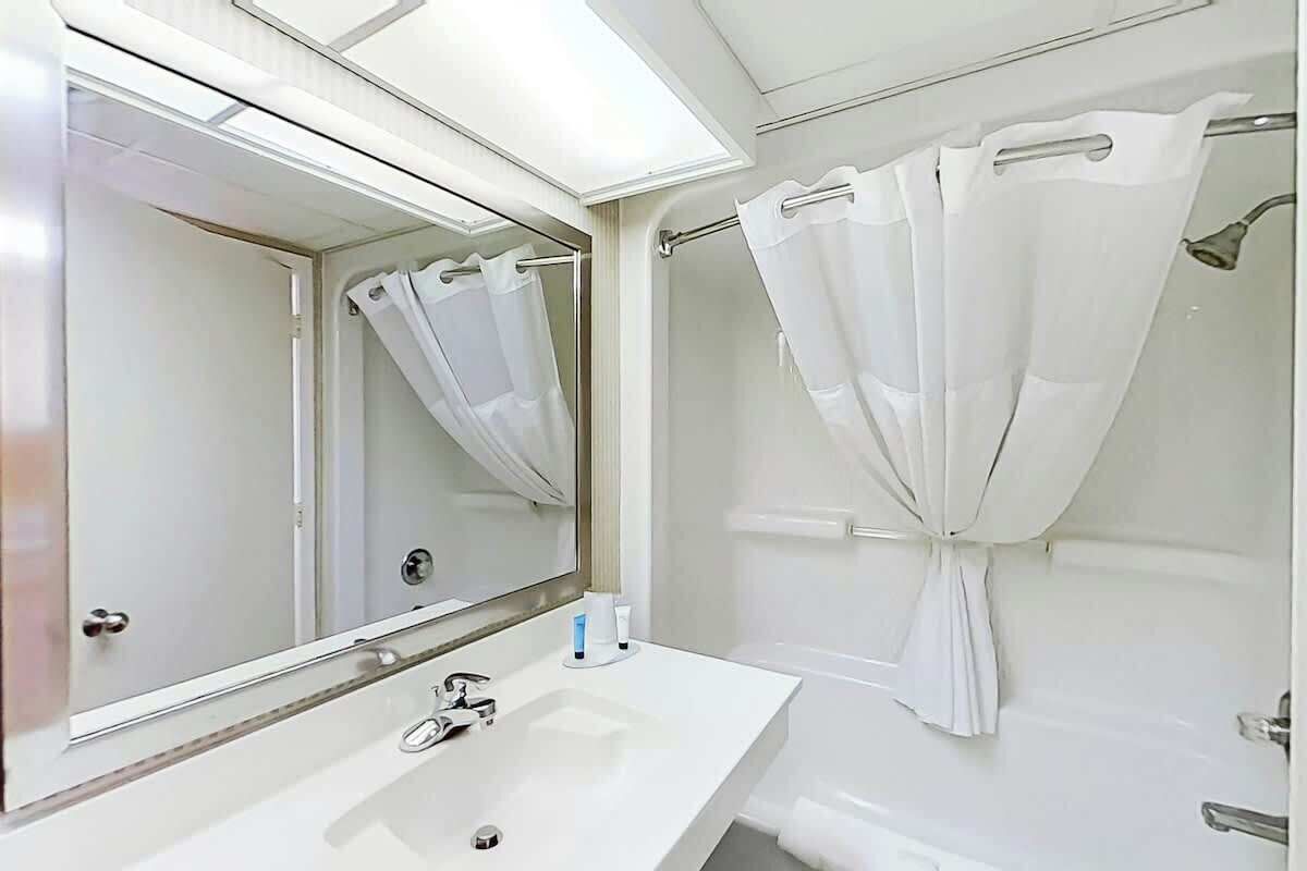 A bathroom with a white sink, mirror, and shower curtain.
