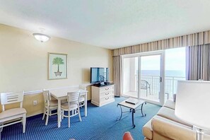 Een hotelkamer met balkon, bureau met stoel, een bank en een televisie.