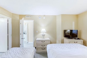 Une chambre d’hôtel avec deux lits, une télévision, une lampe et une commode.
