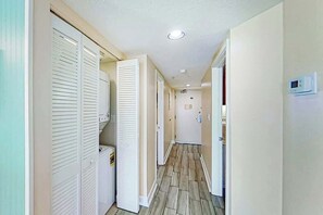 Un couloir avec des portes blanches, un thermostat bien visible et un sol carrelé.