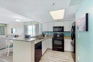 A compact kitchen with a central island, built-in microwave, oven, and dishwasher. - Camelot by the Sea 1601 (Myrtle Beach)