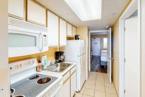Eine kleine Küche mit Mikrowelle, Herd, Spüle und Kühlschrank.