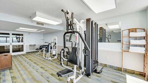 Ein Fitnessstudio mit Trainingsgeräten, einer Spiegelwand und einem Fenster.