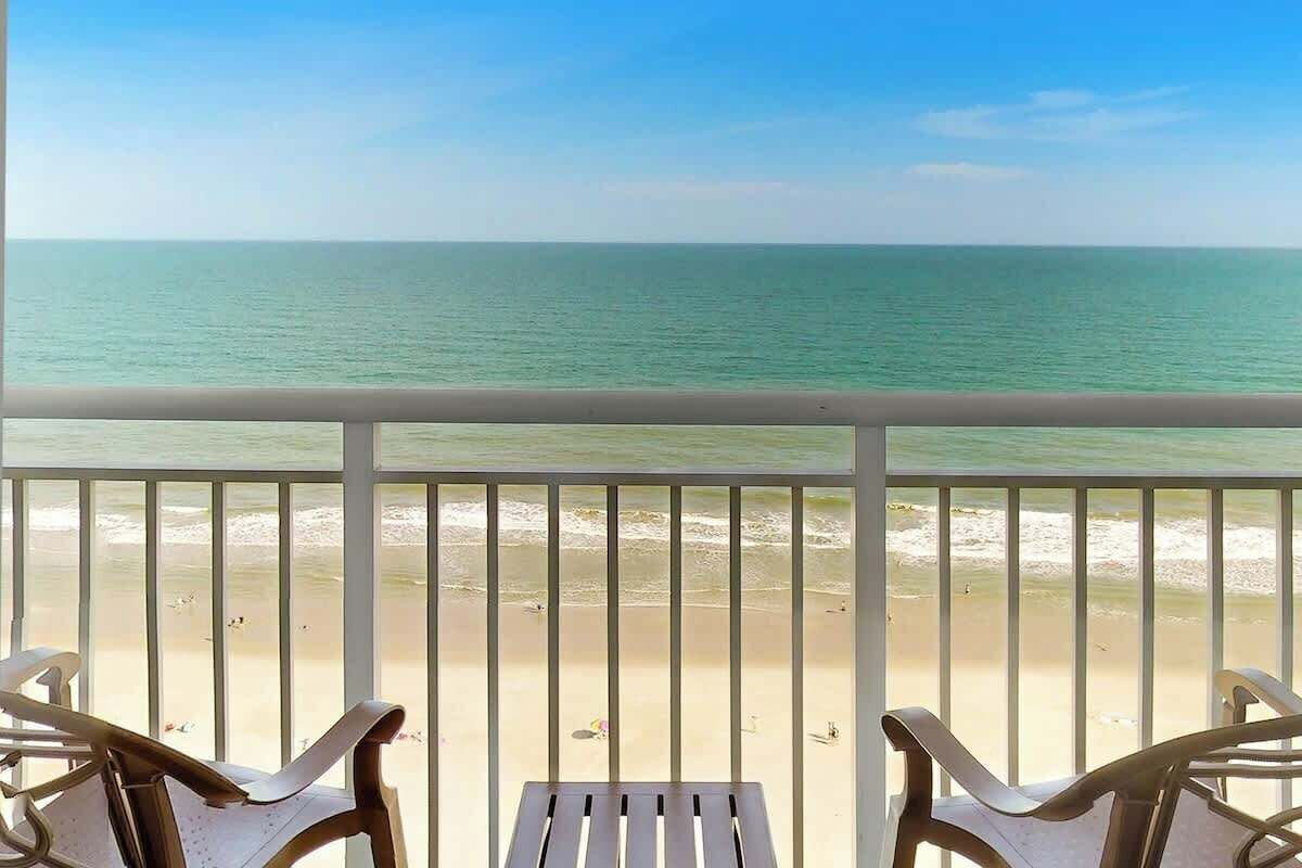 A balcony with a view of the beach and ocean.