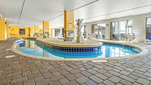 Ein Hallenbad mit gefliestem Rand, einer Statue in der Mitte und einem Boden aus Ziegelsteinen.