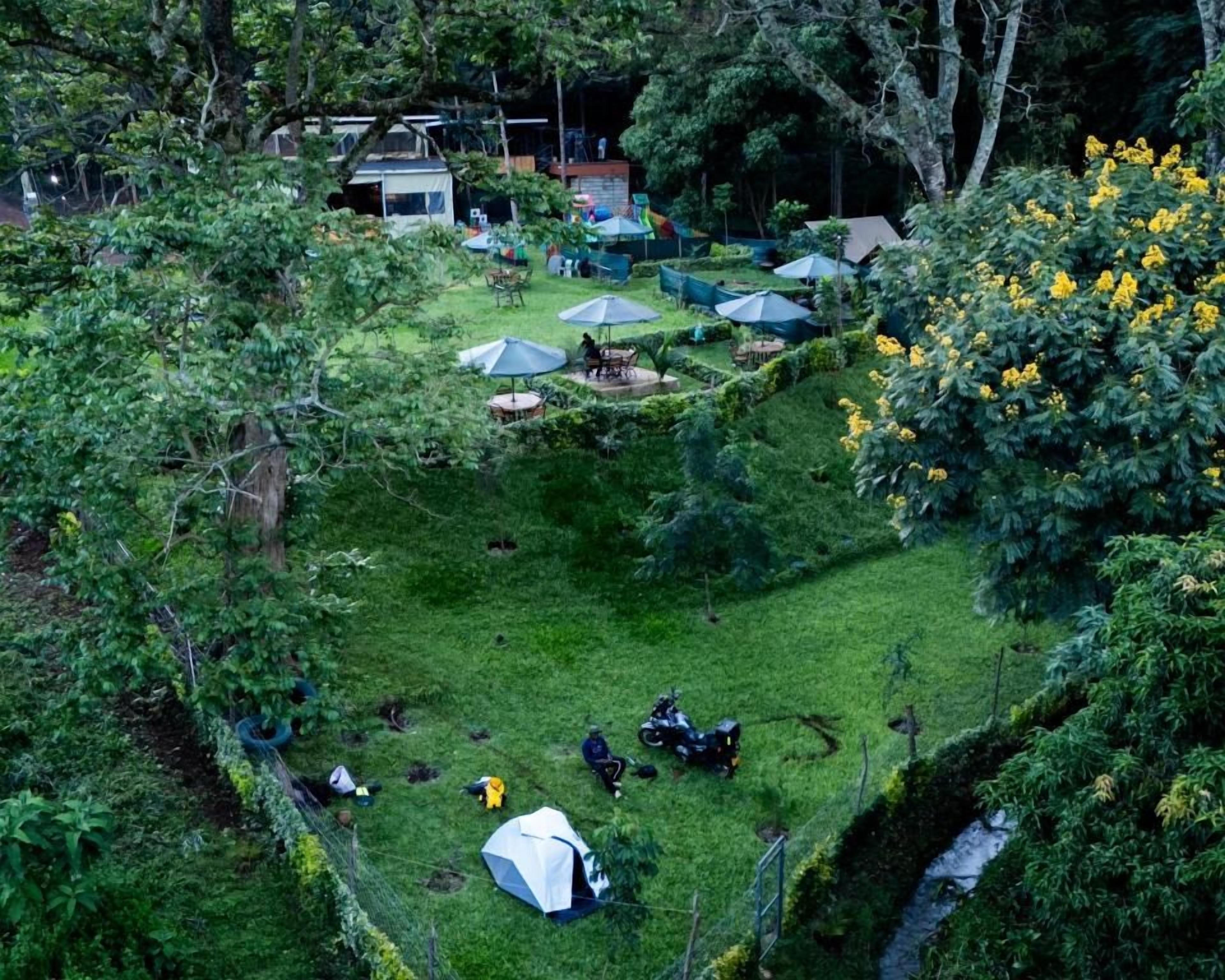 A campsite with tents, a small building, and a grassy area with trees.