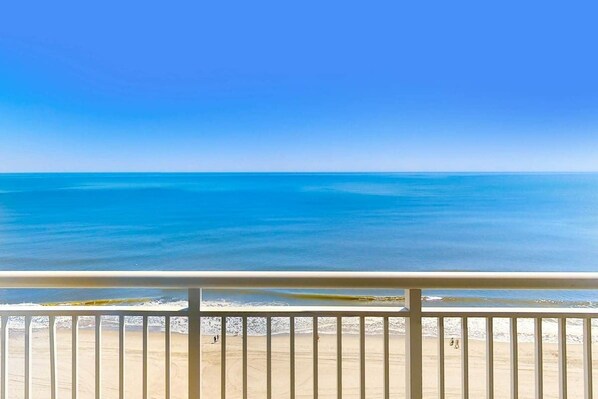 Un balcon avec vue sur une plage et l’océan.