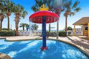 Une piscine avec une fontaine, des palmiers et une vue sur la plage.