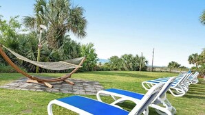 A row of sun loungers with blue cushions, a hammock, and palm trees in the background. - Camelot by the Sea 1603 (Myrtle Beach)