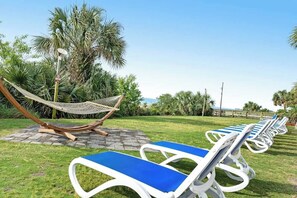 A row of sun loungers with blue cushions, a hammock, and palm trees in the background. - Camelot by the Sea 1603 (Myrtle Beach)