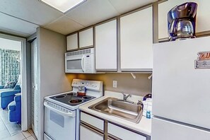 Una kitchenette compacta equipada con estufa, microondas, pileta y refrigerador.