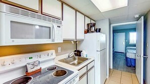 Una cocina compacta equipada con microondas, estufa, fregadero y refrigerador.