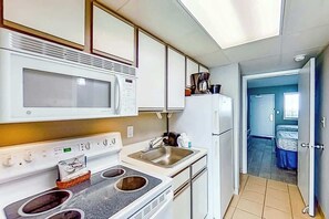 Eine kleine Küche mit Mikrowelle, Herd, Spüle und Kühlschrank.