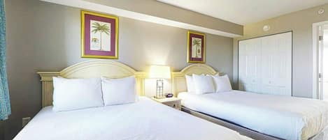 Een hotelkamer met twee bedden, een nachtkastje met een lamp en een deur.