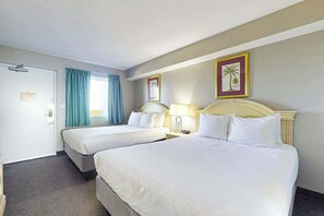 Ein Hotelzimmer mit zwei Betten, einer Tür, einem Fenster mit Vorhängen und zwei Wandlampen.