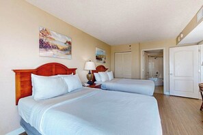 A hotel room with two beds, a painting on the wall, and a door leading to another room. - Carolinian Resort Oceanfront 1132 (Myrtle Beach)