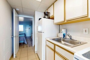 Une cuisine compacte équipée d’un réfrigérateur, d’une machine à café et d’un évier.