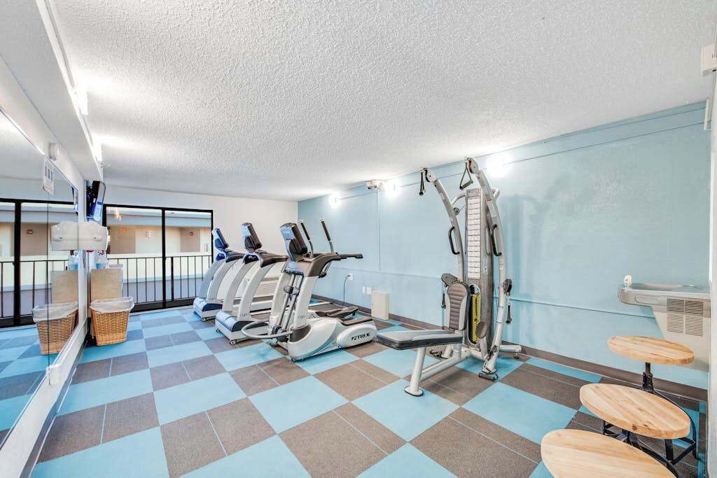 Ein Fitnessraum mit Cardiogeräten, einer Gewichtbank und einem Spiegel.