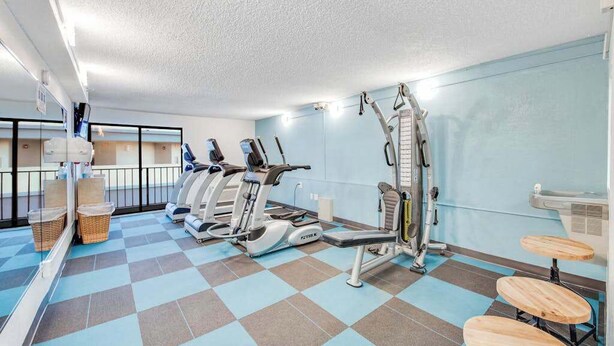 Ginásio com máquinas de cardio, um banco de musculação e um espelho.