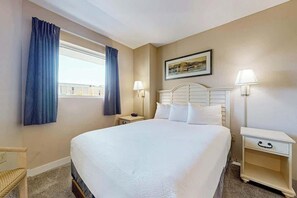 A hotel room with a large bed, two bedside tables, a chair, and a window with curtains. - Harbourgate Unit 0130 (North Myrtle Beach)