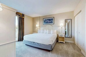 A hotel room with a bed, bedside lamps, a nightstand, a mirror, and a window with curtains. - Harbourgate Unit 0130 (North Myrtle Beach)