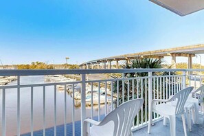 A balcony with white chairs overlooking a marina and a bridge. - Harbourgate Unit 0130 (North Myrtle Beach)