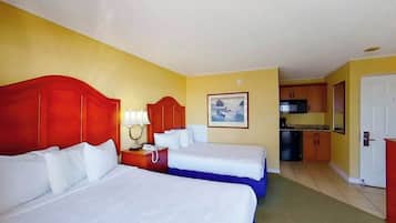 A hotel room with two beds, a small kitchenette, and a bathroom.