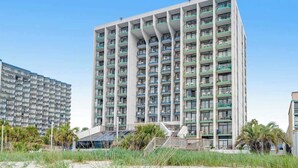 Un hôtel de grande hauteur doté de nombreux balcons, d’une façade sobre et situé en bord de mer.