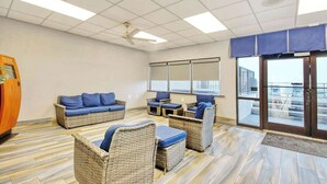 Une pièce meublée de mobilier en osier, dotée d’un ventilateur de plafond et offrant une vue à travers des portes vitrées.