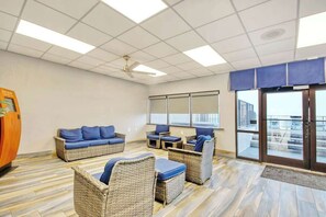 Ein Zimmer mit Korbmöbeln, einem Deckenventilator und Blick durch Glastüren.