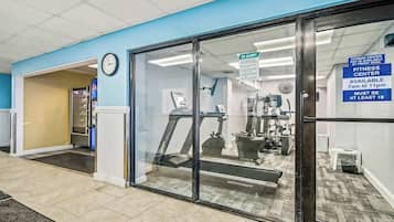 A fitness center with a treadmill, weights, and a sign indicating availability from 7am to 11pm.