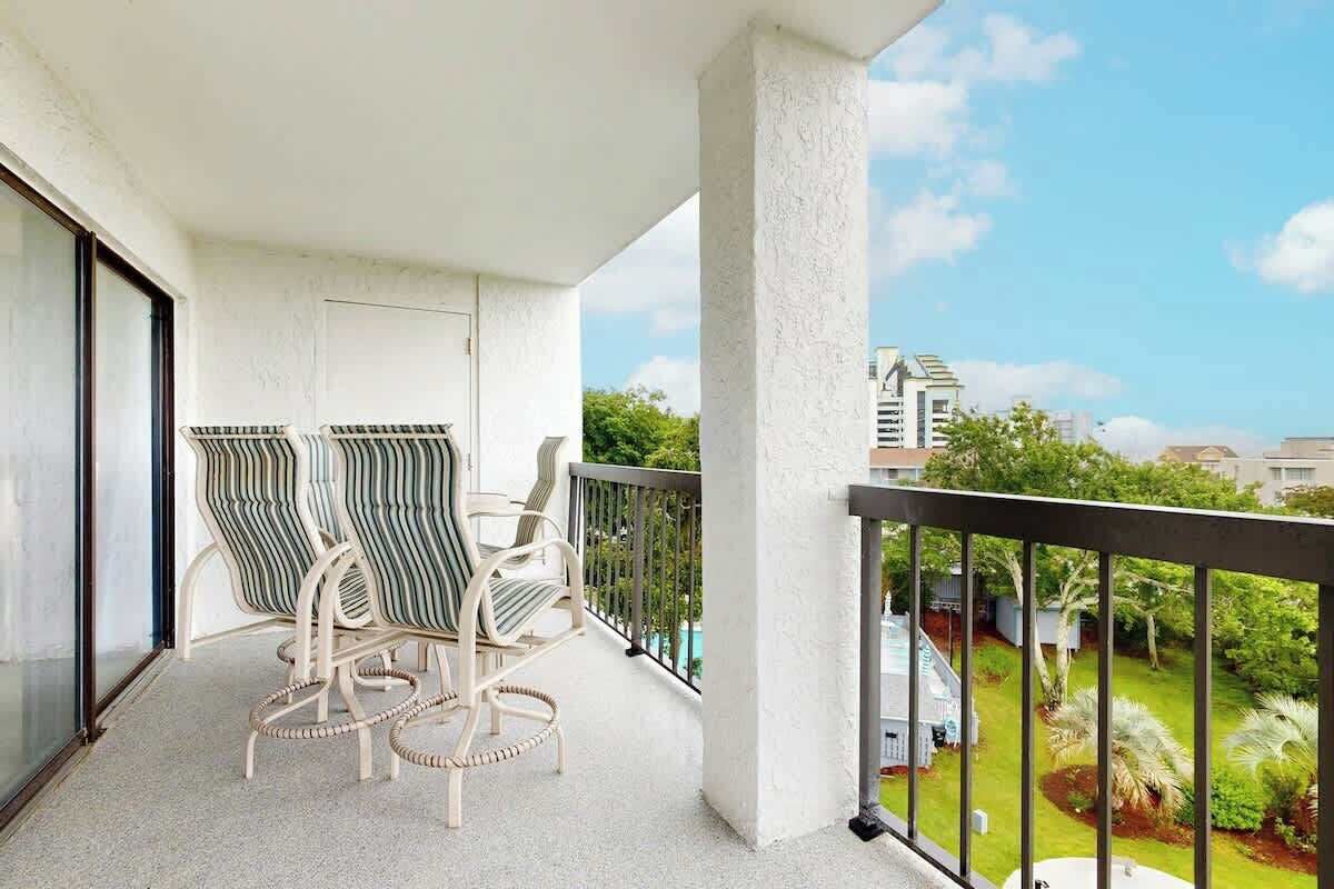 A balcony with two chairs and a view of a residential area.