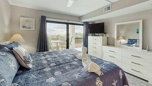 Une chambre d’hôtel avec un lit, une commode, une télévision et un balcon offrant une vue.