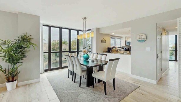 Un espace de repas moderne, doté d’une grande table, de chaises et offrant une vue à travers les portes vitrées.