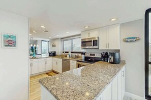 Eine moderne Küche mit weißen Schränken, Granit-Arbeitsplatten und Edelstahlgeräten.