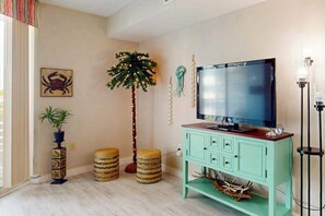 Ein Wohnzimmer mit Fernseher, einer Zimmerpflanze und einem Wandregal.
