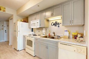 Eine moderne Küche mit weißen Geräten, einer Marmorarbeitsplatte und einem an der Wand befestigten Schild mit der Aufschrift 'Coffee'.