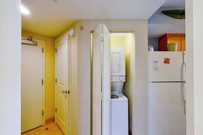 Eine kompakte Küche mit Waschmaschine, Kühlschrank und Mikrowelle.