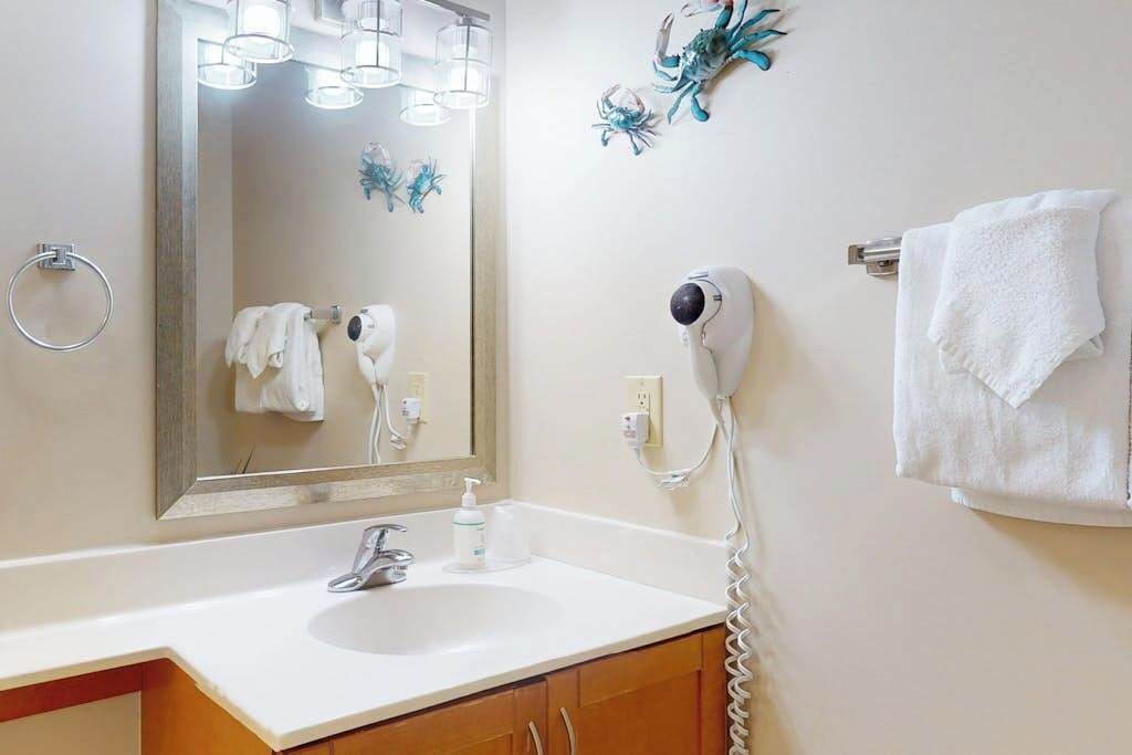 A bathroom with a sink, mirror, towel rack, and a hairdryer.